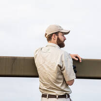 A Bushwise students looks over a bridge railing towards a lake view.