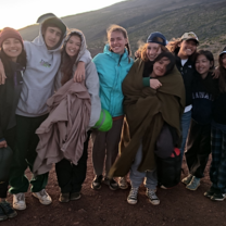 students outside wrapped up in blankets by sunset 