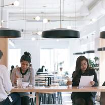 One male and two female students sit at a long table in a cafe