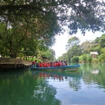 A group of students in red life jackets in a boat on a canal surrounded by lush vegetation