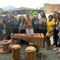 A group of people pose for a photo in front of assorted musical instruments in a courtyard