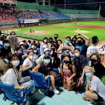A large group of students posing for a picture at a baseball stadium at night