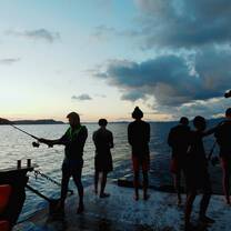 A group fishes during a sunset