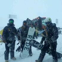 A group stands in the snow with snowboards