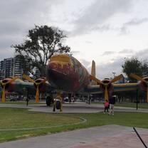 Large airplane model displayed in a public park in Quito, Ecuador, with mountains and cityscape in the background