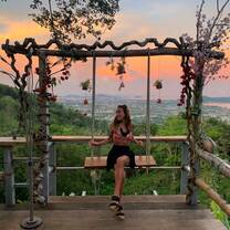 A teacher poses on a large wooden swing at a viewpoint in Khao Yai
