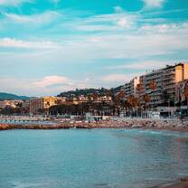 A sunny beach with houses rising along it