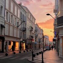 Sun sets on a street lined with tall stone buildings on either side