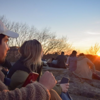 Young students are sitting while the sun sets in the background
