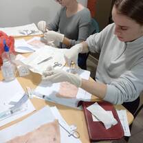 Volunteers concentrate during a medical skills class where they practice suturing on pig skin.