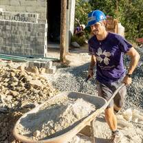 Volunteer moves wheelbarrow full of dirt
