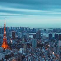 Panorama image a metropolis skyline with numerous high rises visible dwarfed by a tall red and white tower