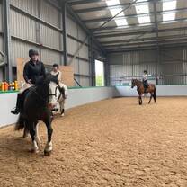 A student riding a horse through open fields surrounded by Scottish hills as part of the summer study program.