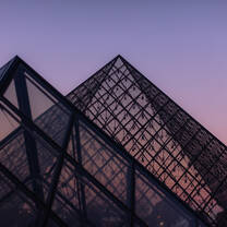 The sun rising over the famed glass pyramids of Le Louvre
