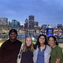 four students in front of Baltimore skyline