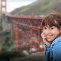 Smiling young woman poses in front of Golden Gate Bridge