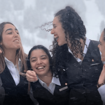 Group of hospitality-uniformed young women laughing in the snow