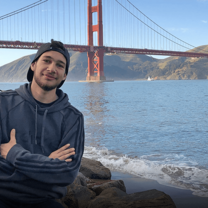 Young man poses in front of Golden Gate Bridge in San Francisco, California