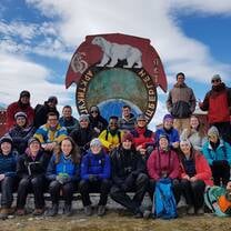 A group of students are sitting in front of a sign with a polar bear.