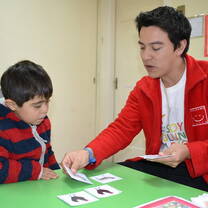 A volunteer teacher working with a child in a classroom.