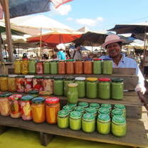A person standing in front of a stall of jars filled with sauces and vegetables.