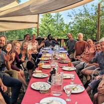 A diverse group of 16 people enjoying a lovely summer dinner outside on the deck