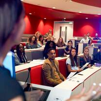 Woman lecturing students in lecture theatre, focus midground