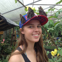 A student wearing a baseball cap with butterflies sitting on top of it