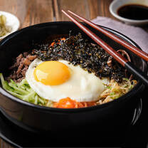 A shot of bimimbap with chopsticks resting on the edge of the bowl