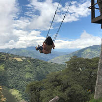 A student swinging on a swing overlooking a valley