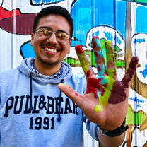 A student holding up a hand with paint on it 