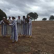 Men wearing white and blue striped robes holding baskets