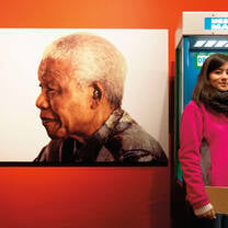 A woman at a call box next to a photo of Nelson Mandela