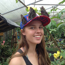 A student wearing a baseball cap with butterflies sitting on top of it