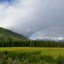 Rainbow over mountain and field. 