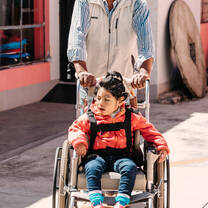 Young girl in wheelchair is guided by volunteer