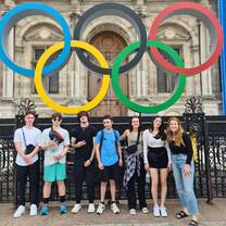A group poses for a photo under the Olympic Rings