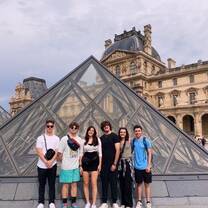 A group stands for a photo in front of the Louvre Pyramid