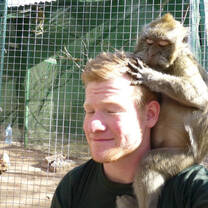 A monkey sitting on a white man's shoulder