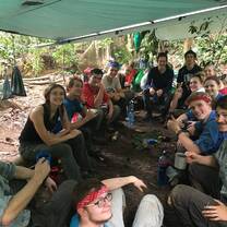 A group poses for a photo under a lean to