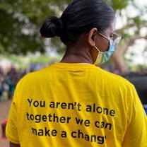 person facing away from camera with a shirt that says "You aren't alone. Together we can make a change" printed on the back