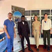 four members of the medical team standing in front of a large banner