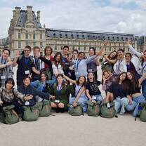 large group posing in front of Louvre in Paris