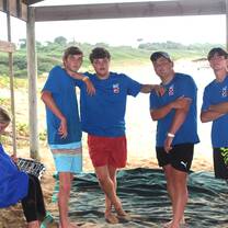 four boys standing under a tent on the beach