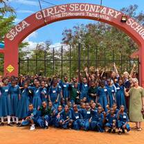 2023 volunteer group and students under SEGA School sign 