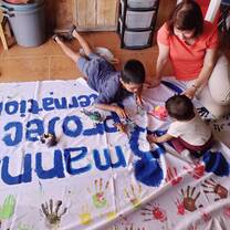 Voluneer painting on sign on floor with kids