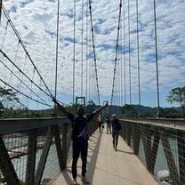 Volunteer standing on bridge with arms up looking happy