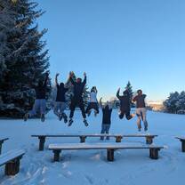 Team members jumping off a bench into the snow
