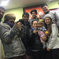 A Nepali family smiles at the camera with two American volunteers