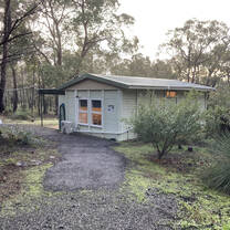 A cabin sits in the evening sunshine among a number of trees